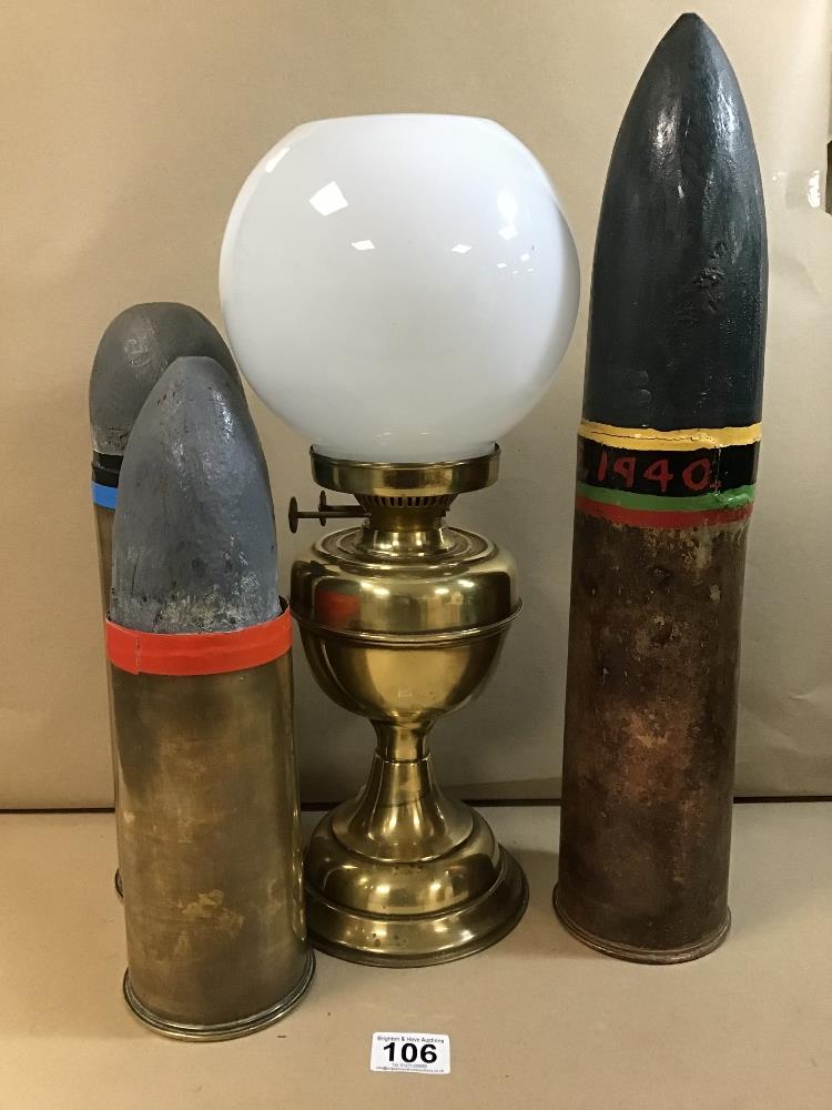 THREE BRASS SHELL CASES WITH LATER PAPIER MACHE PROJECTILE ENDS, TOGETHER WITH A BRASS OIL LAMP WITH