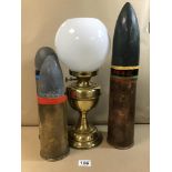 THREE BRASS SHELL CASES WITH LATER PAPIER MACHE PROJECTILE ENDS, TOGETHER WITH A BRASS OIL LAMP WITH