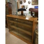 A 20TH CENTURY WOODEN DISPLAY CAB BOOK SHELF WITH GLASS SLIDING DOORS TO THE FRONT, 122CM WIDE