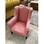AN EARLY PINK ARMCHAIR RAISED UPON FOUR WOODEN FEET WITH CASTORS