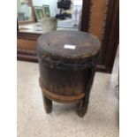 AN ANTIQUE WOODEN TRIBAL DRUM OF CIRCULAR FORM WITH SKIN TOP AND ON LEGS 38CMS HIGH