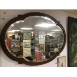 A BEVELLED EDGED VINTAGE MIRROR WITH LEAF DECORATION ON THE BORDER