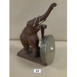 AN AFRICAN CARVED WOODEN ELEPHANT GONG, ITS TUSK HOLDING THE METAL GONG, WITH CARVED BONE TUSKS,