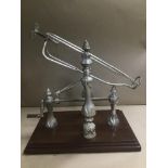 A SILVER PLATED WINE BOTTLE DECANTING CRADLE MOUNTED ON WOODEN BASE, 37CM HIGH