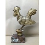 AN ORNATE GILT PLASTER FIGURE OF A COCKERAL RAISED UPON MARBLE PLINTH, 33CM HIGH (AF)