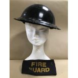 A MID CENTURY MILITARY HELMET, TOGETHER WITH A FIRE GUARD ARM BAND