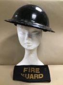 A MID CENTURY MILITARY HELMET, TOGETHER WITH A FIRE GUARD ARM BAND