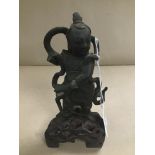 AN EARLY ORIENTAL CAST BRONZE FIGURE OF A MILITARY MAN, RAISED UPON A WOODEN BASE, 18CM HIGH (HAND