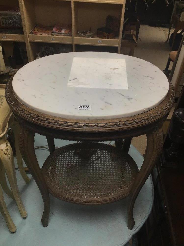 A FRENCH ORNATE OVAL SIDE TABLE WITH A WHITE MARBLE TOP AND A WICKER SHELF ON TURNED OUT LEGS