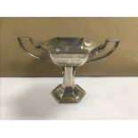 AN ART DECO SILVER TWO HANDLED HEXAGONAL CUP RAISED UPON PEDESTAL, HALLMARKED SHEFFIELD 1941 BY