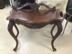 AN ORNATE REPRODUCTION CONSOLE TABLE WITH TURNED OUT LEGS IN MAHOGANY