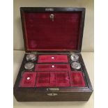 A 19TH CENTURY MAHOGANY TRAVELING VANITY SET, THE LID OPENING TO REVEAL FOUR GLASS POTS, THREE