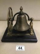 A BRASS ROCKING DESK BELL, MOUNTED ON WOODEN BASE