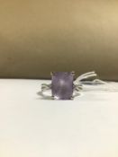 A MODERN 18CT WHITE GOLD LADIES RING WITH A LARGE CLAW SET EMERALD CUT AMETHYST FLANKED ON EITHER