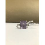 A MODERN 18CT WHITE GOLD LADIES RING WITH A LARGE CLAW SET EMERALD CUT AMETHYST FLANKED ON EITHER