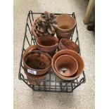 A WROUGHT IRON VINTAGE MILK CRATE WITH SOME TERRACOTTA GARDEN POTS