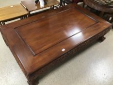 A LARGE LOW COFFEE TABLE ORIENTAL CARVING TO THE SIDES WITH BALL AND CLAW FEET