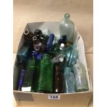 A COLLECTION OF COLOURED GLASS BOTTLES SOME WITH NAMES INCLUDING BOOTS, EIFFEL TOWER, POISON AND