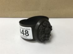 A BLACK JET STYLE BANGLE WITH CARVED CAMEO TO TOP OF FRUIT