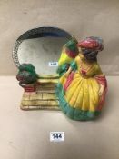 A VINTAGE PLASTER FIGURE OF A LADY STANDING NEXT TO A MIRROR