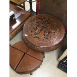 A HARD WOOD ORIENTAL CARVED SCENES ROUND TABLE WITH A NEST OF FOUR UNDER SIDE TABLES