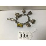 A HEAVY 925 SILVER CURB LINK CHARM BRACELET WITH NUMEROUS HANGING CHARMS, INCLUDING SEAL, NOVELTY