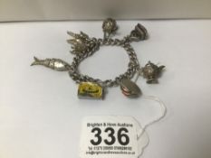 A HEAVY 925 SILVER CURB LINK CHARM BRACELET WITH NUMEROUS HANGING CHARMS, INCLUDING SEAL, NOVELTY