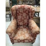 AN EARLY 20TH CENTURY WINGBACK ARMCHAIR ON CASTORS