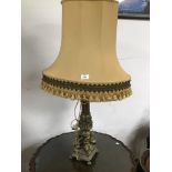 A VINTAGE TABLE LAMP WITH A BRASS BASE DECORATED WITH CHERUBS ON COLUMNS (VINTAGE SHADE)