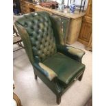 A VINTAGE GREEN BUTTON BACK LEATHER WING BACK CHAIR