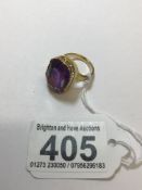A LARGE SOLITAIRE OCTAGON-CUT AMETHYST STONE CLAW SET IN A YELLOW METAL MOUNT RING NO HALLMARK BUT