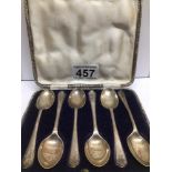 A CASED SET OF HALLMARKED SILVER TEASPOONS BY WALKER AND HALL WITH GOLF CLUBS EMBOSSED ON THEM