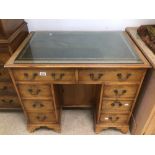 AN EARLY 20TH CENTURY KNEE HOLE DESK WITH EIGHT DRAWERS AND CENTER CUPBOARD AND GREEN LEATHER TOP