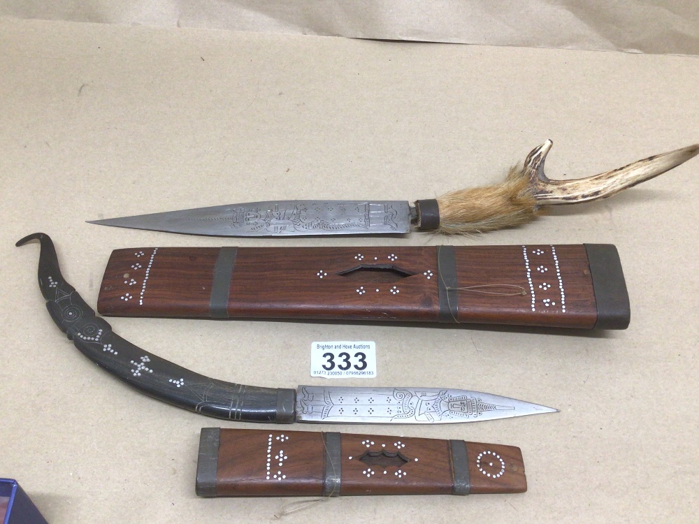 TWO EASTERN DAGGERS WITH SHEATHS ONE WITH A HORN CARVED HANDLE WITH MOTHER OF PEARL INLAY AND ONE