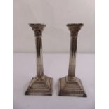 A pair of silver Corinthian column table candlesticks on stepped square bases with beaded borders,