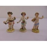 Three Meissen figurines of putti holding flowers on raised naturalistic bases, marks to the bases