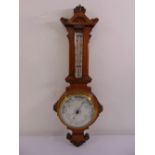 A carved oak cased banjo aneroid barometer and thermometer with white enamel dials and brass bezel