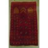 A Middle Eastern wool carpet red ground with repeating geometric patterns, 121 x 75.5cm