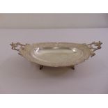 A continental white metal oval fruit dish, chased with putti, flowers, scrolls and leaves, the two