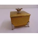 An engine turned gilded metal musical jewellery box with mirrored hinged cover on four leaf