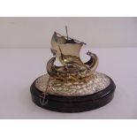 A white metal continental model of a Viking ship on raised oval wooden base