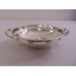 A silver arts and crafts hand hammered bowl, strap side handles and border with applied rosettes