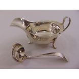 A silver sauce boat, oval, cut edge with loop handle on three scroll legs, Sheffield 1935 and a