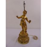 A gilded metal figural table lamp of a young girl holding flowers, on raised circular base