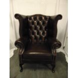 A leather wing back armchair on four scroll legs