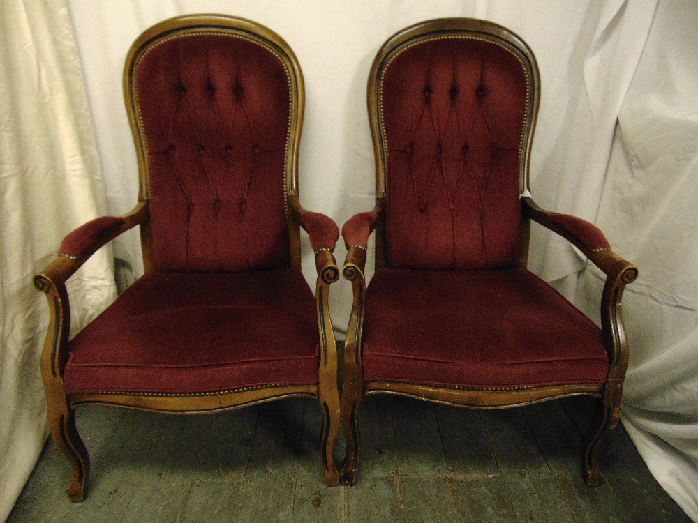 A pair of mahogany button back upholstered armchairs on scroll legs