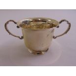 A silver porringer of cylindrical form with two beaded double scroll side handles on flared circular