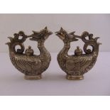 A pair of oriental white metal oil flagons in the form of stylised birds, chased with stylised