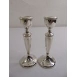 A pair of silver table candlesticks, tapering cylindrical with vase form nozzles on raised