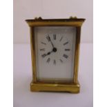 A brass carriage clock of customary form white enamel dial with Roman numerals